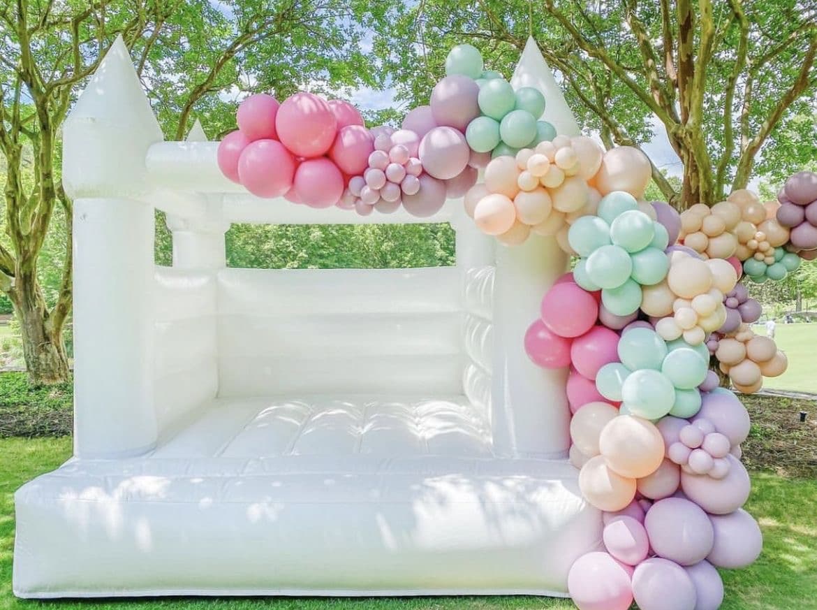 White bounce house with pastel balloon garland at a Miami event